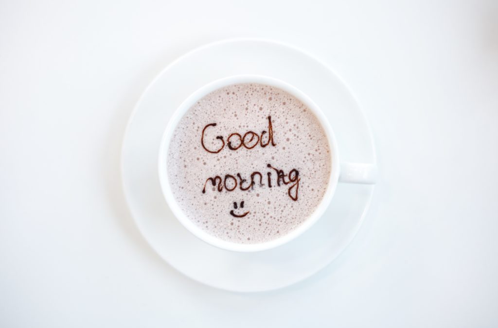 Good morning coffee with a smily face, white saucer and table